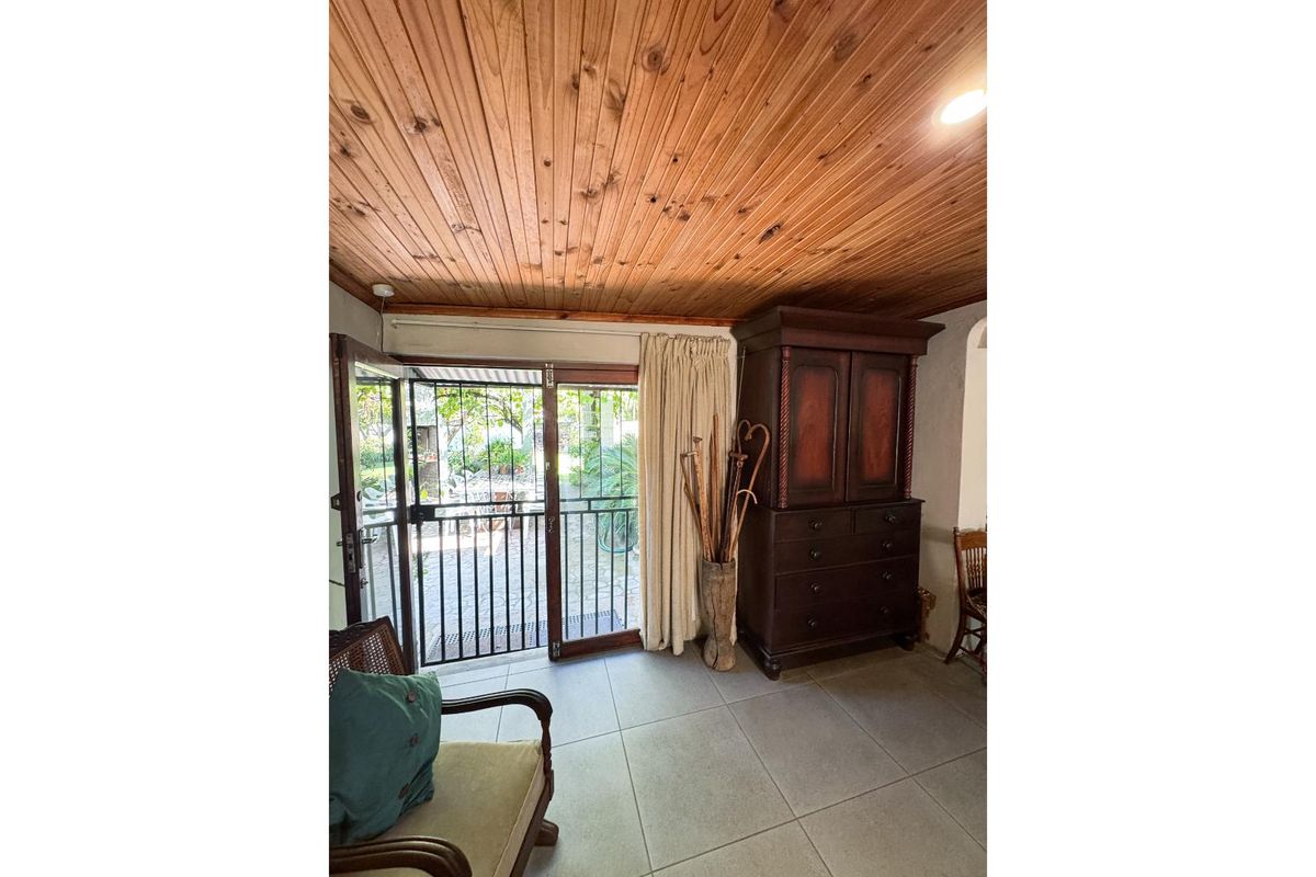 Living area featuring a warm timber tongue and groove ceiling, tiled flooring, and direct access to the outdoor patio through a security gate.