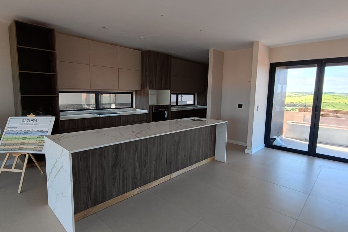 Modern open-plan kitchen featuring sleek cabinetry, stone-topped island, and large sliding doors leading to an outdoor area with scenic views.