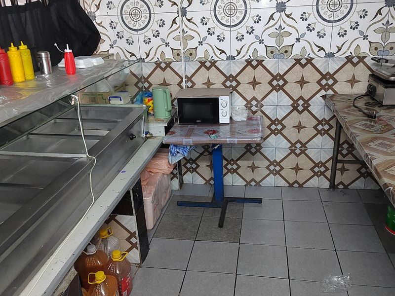 A functional kitchen area featuring patterned wall tiles, tiled flooring, and built-in food preparation equipment.