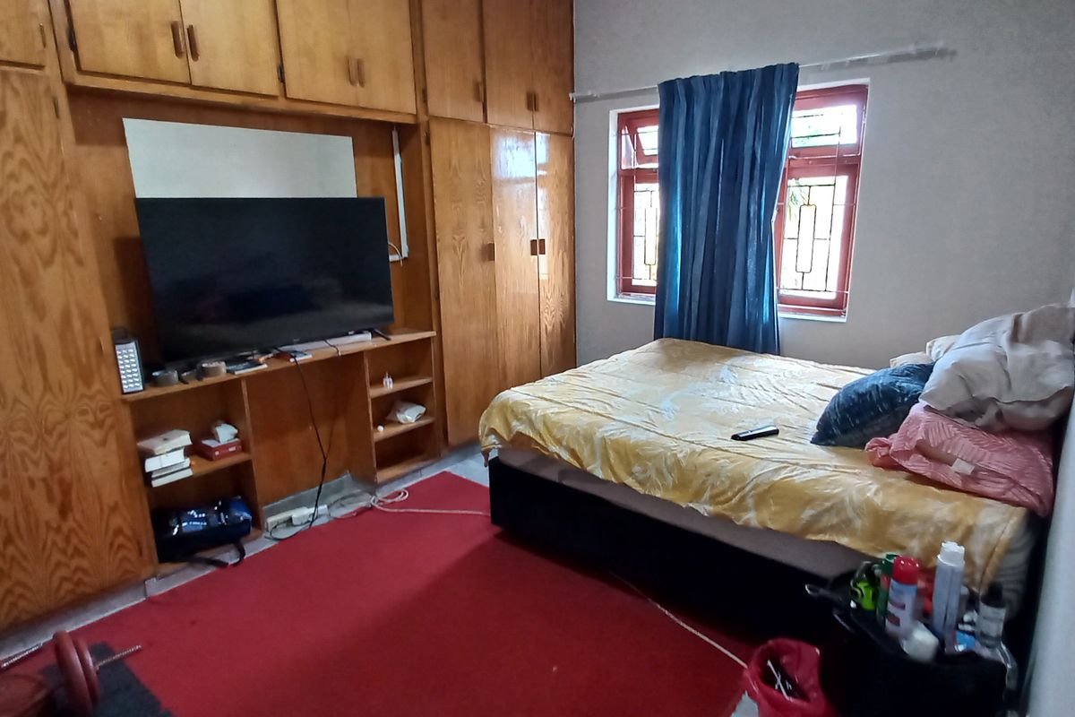 Bedroom featuring extensive built-in wooden cabinetry and security bars on the window, offering functional storage space.