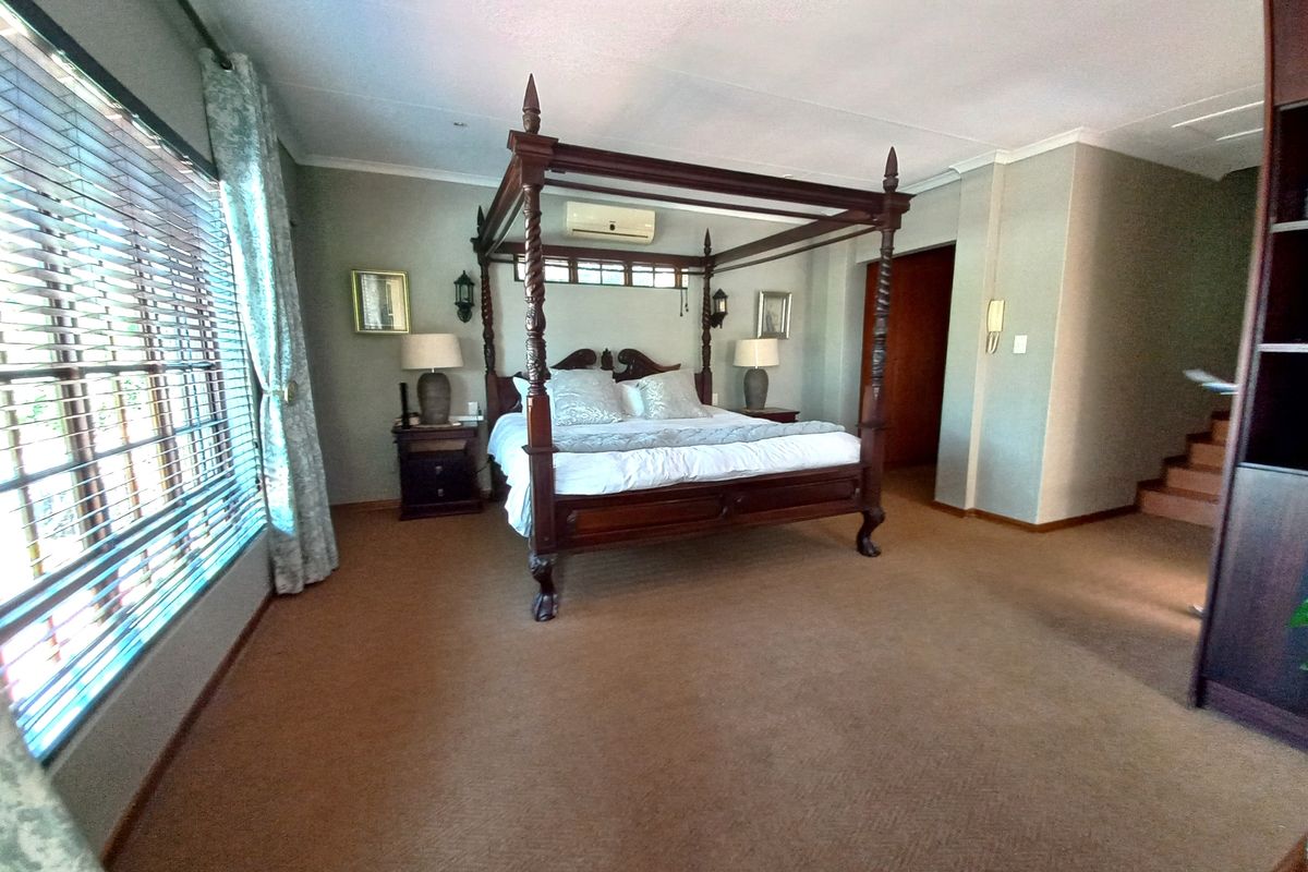 Spacious bedroom featuring carpeted flooring, a split-system air conditioner, and built-in shelving, offering a comfortable and functional living space.