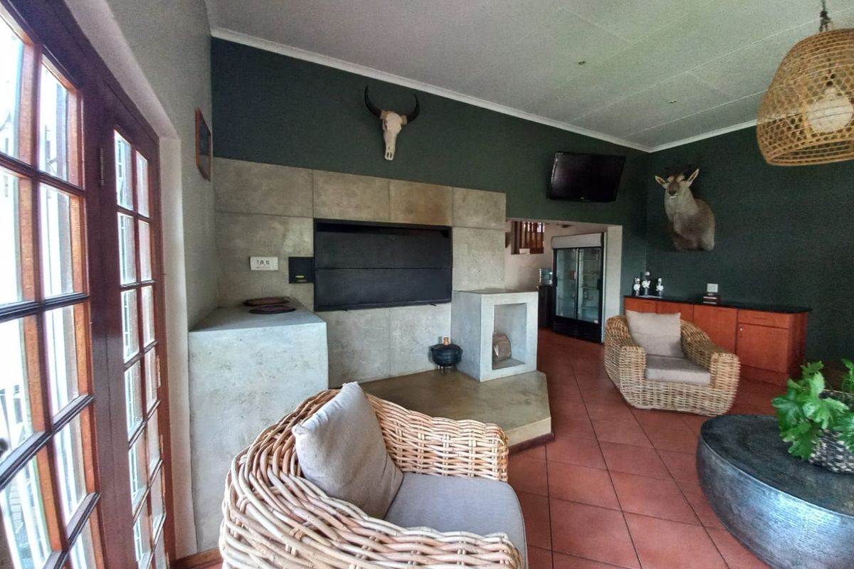 Spacious living area featuring a large built-in fireplace, terracotta tiled flooring, and direct access to the outdoors through classic wooden french doors.