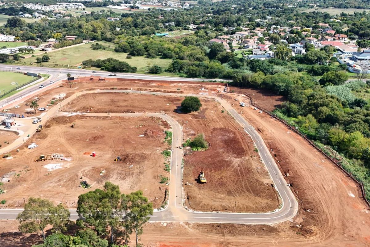 Aerial view of a residential development site showing cleared land, internal road infrastructure, and surrounding neighborhood.