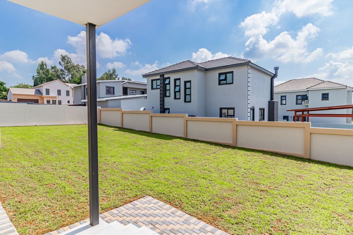 A view of the rear garden and lawn area, featuring a paved patio section and perimeter boundary walls.
