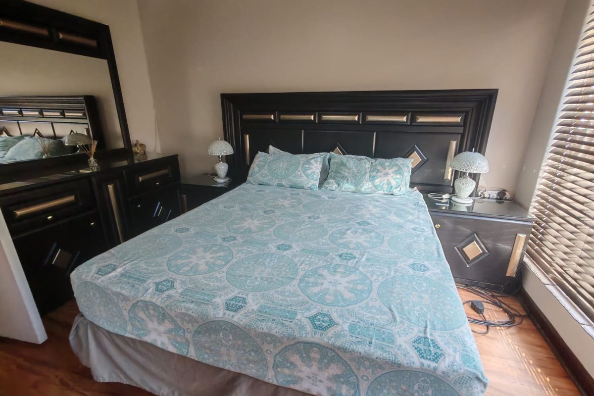 A bedroom featuring laminate flooring and venetian blinds, providing a functional space with neutral wall tones.