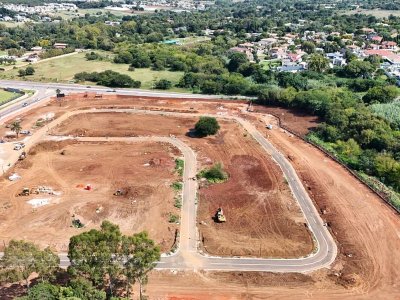 Aerial view of a residential development site showing cleared land, internal road infrastructure, and surrounding neighborhood.