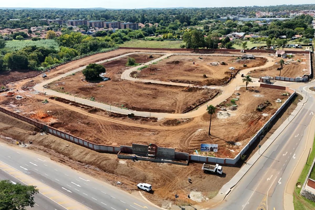 Aerial view of a residential development site featuring cleared land, internal road infrastructure, and perimeter walling in a suburban setting.