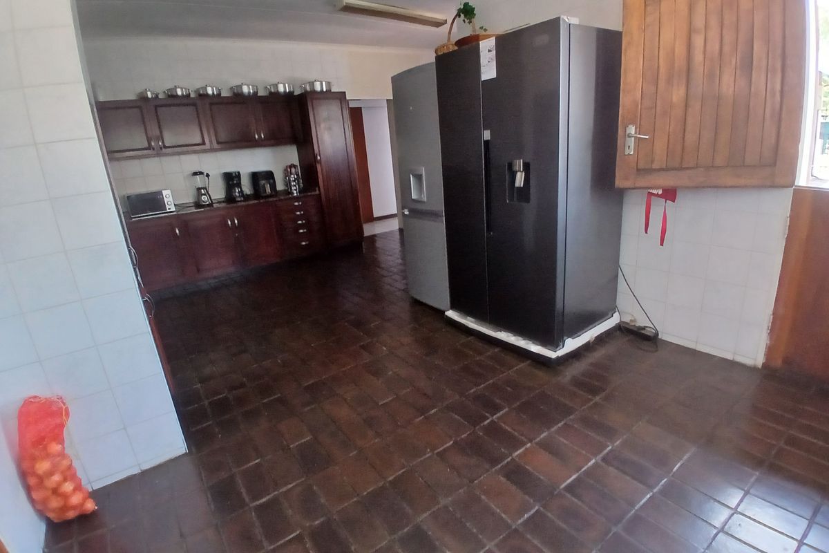 A functional kitchen featuring dark wood cabinetry, tiled flooring, and tiled wall finishes, providing a practical workspace with ample storage.