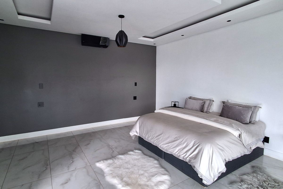Spacious bedroom featuring modern tiled flooring, a recessed ceiling with downlights, and a wall-mounted split-system air conditioning unit.
