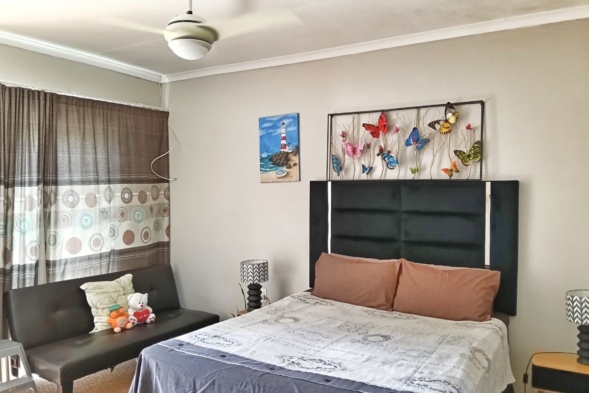 A bedroom featuring a ceiling fan and neutral wall finishes, showing visible signs of ceiling water staining.