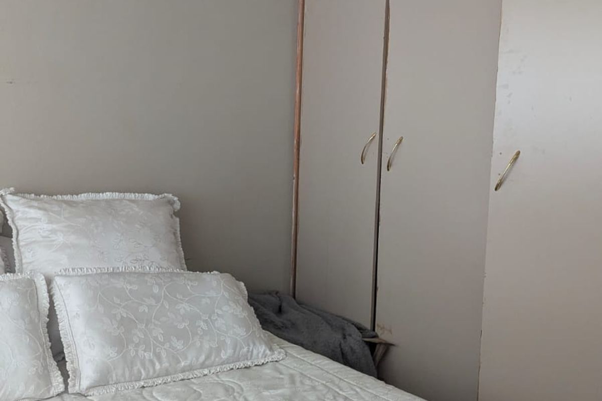 A bedroom featuring built-in wardrobes with neutral cabinetry and a decorative ceiling light fixture.