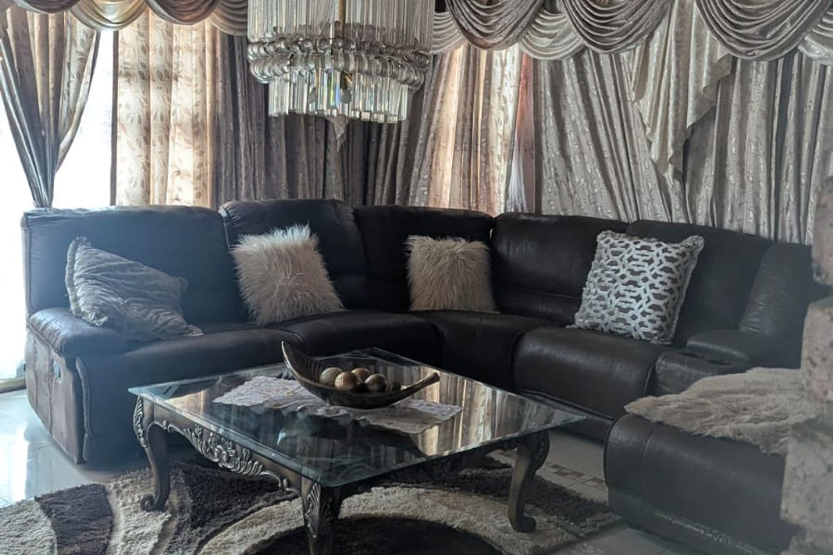 Spacious living room featuring a polished tile floor, a distinctive timber-clad ceiling, and a large central crystal chandelier.