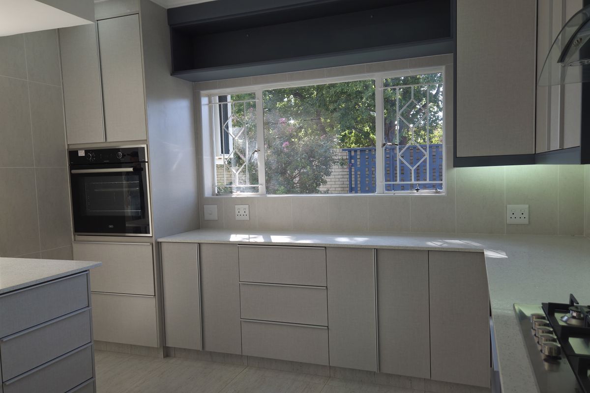 Modern kitchen featuring sleek cabinetry, stone countertops, built-in oven, gas hob, and under-cabinet lighting, offering a clean and functional workspace.