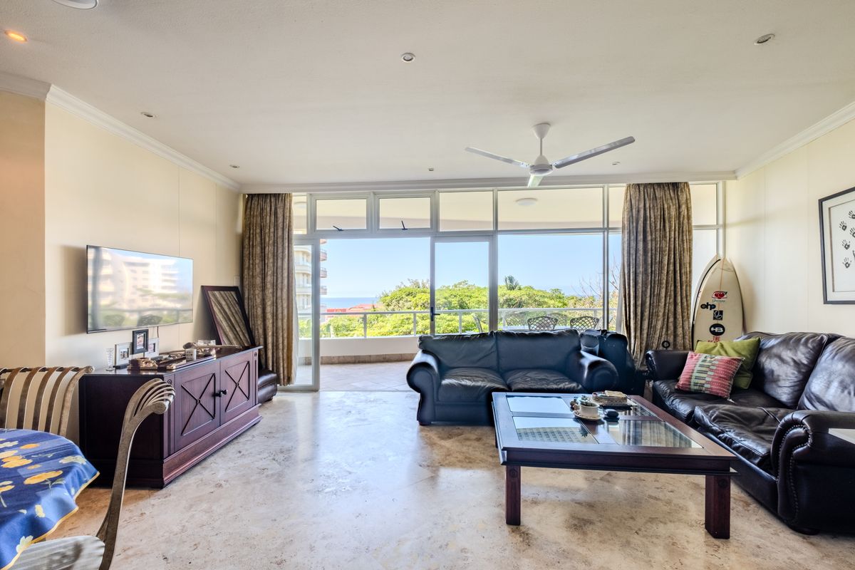Spacious living room featuring stone flooring, recessed lighting, and large sliding glass doors that open onto a balcony with scenic views.