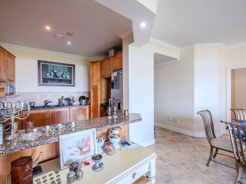 Open plan kitchen and dining area featuring wooden cabinetry, granite countertops, and stone tile flooring with recessed lighting and coved cornicing.