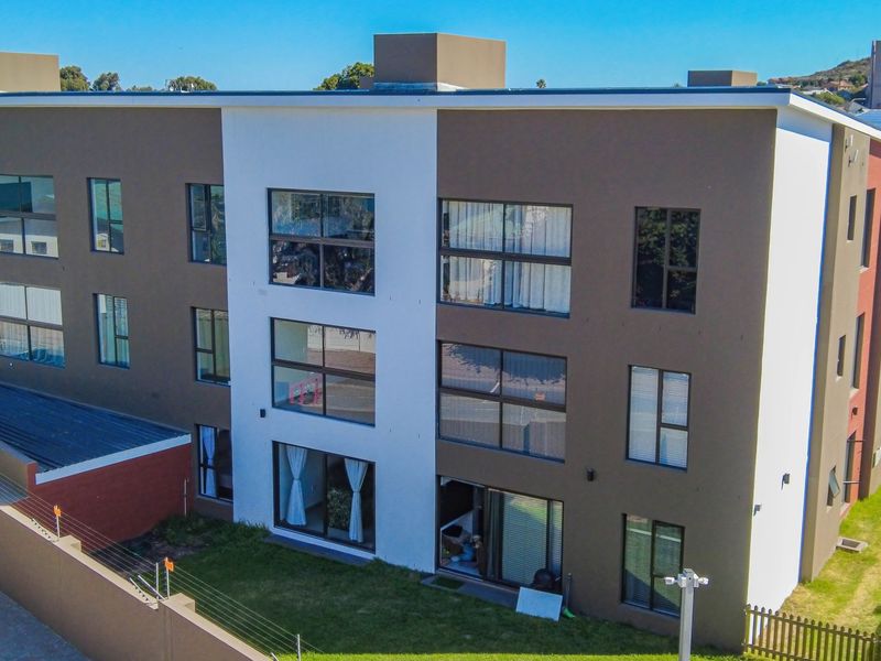 Aerial view of a modern multi-story apartment building featuring a contemporary facade with large windows and sliding glass doors leading to a rear garden.