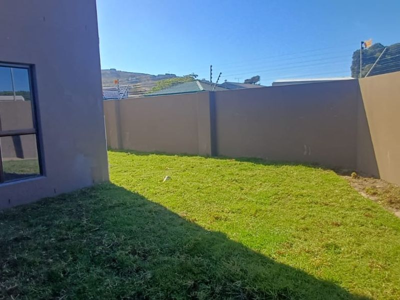 A private rear garden area featuring a lawn and high boundary walls, providing a secure outdoor space for the apartment.