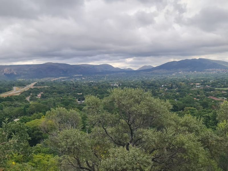 A scenic elevated view overlooking a lush green landscape with distant mountains under a cloudy sky.