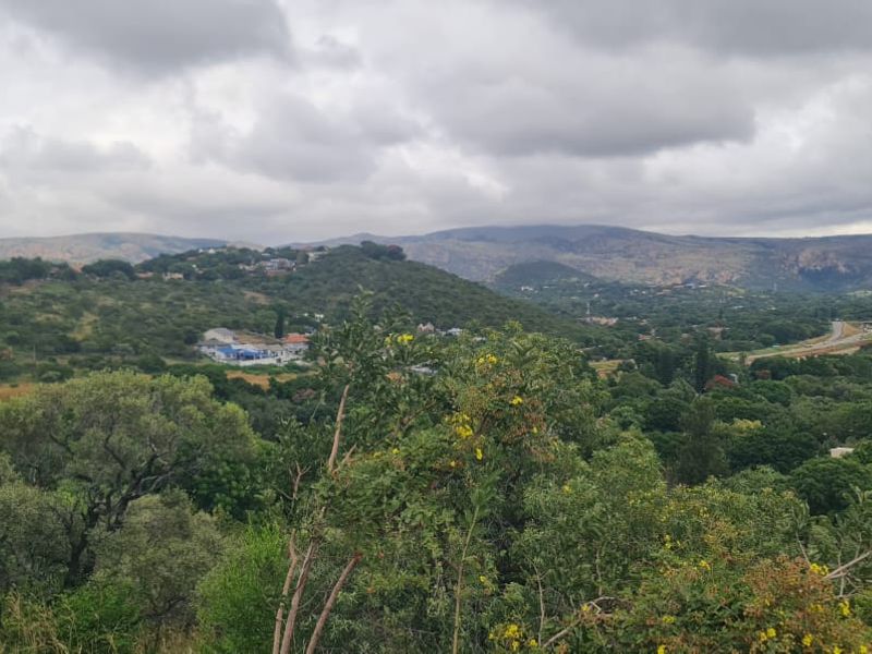 A scenic landscape view overlooking a lush, green valley with distant hills and a cloudy sky.