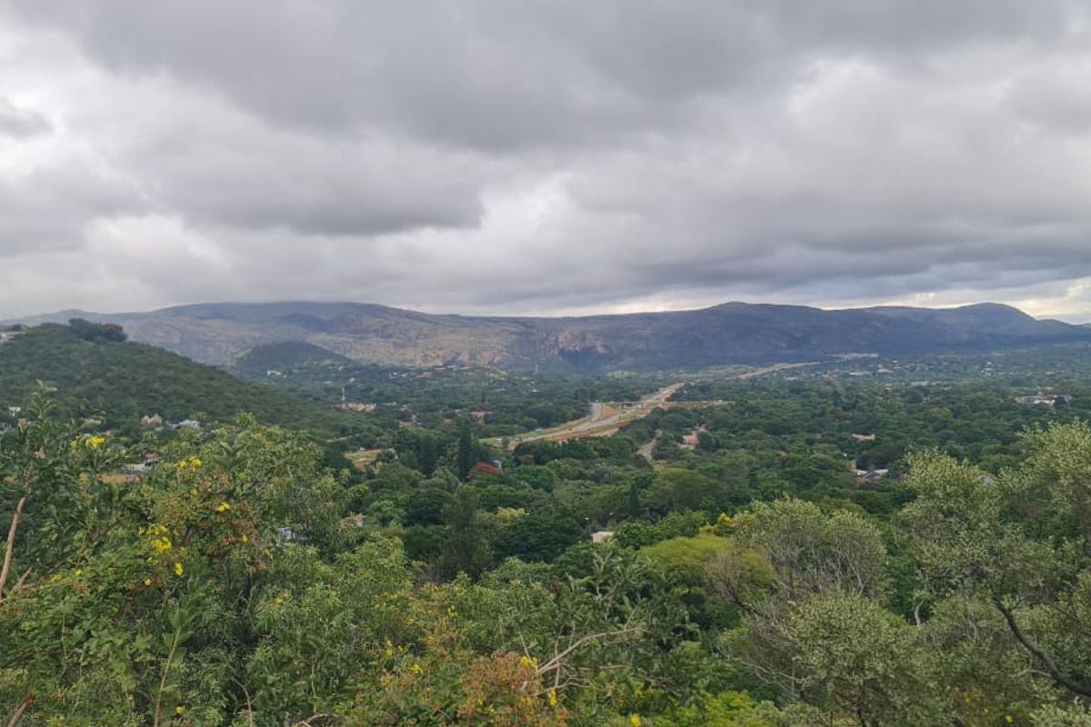 A scenic landscape view overlooking a lush green valley with distant mountains under a cloudy sky.
