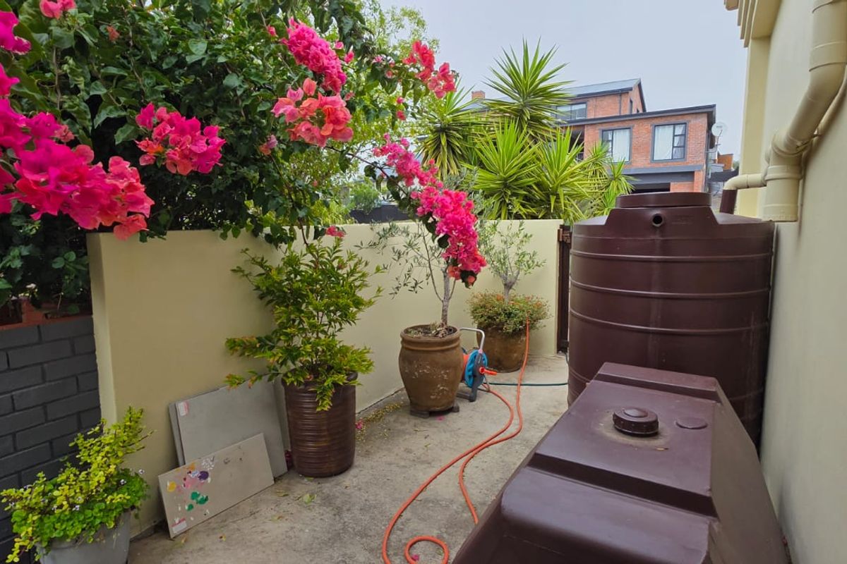 A side or rear exterior area featuring a concrete surface, boundary wall, and large water storage tanks.