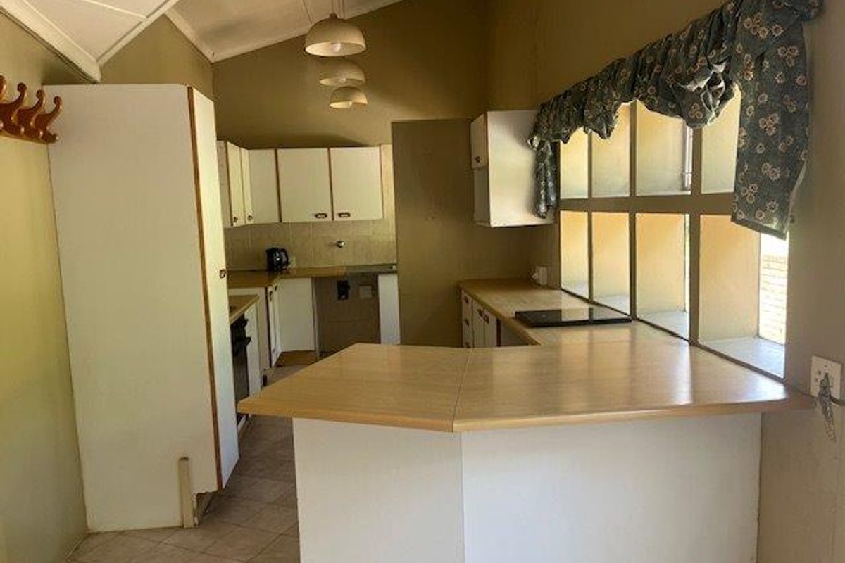 A dated kitchen featuring a U-shaped layout with laminate countertops, built-in cabinetry, and a breakfast bar area.