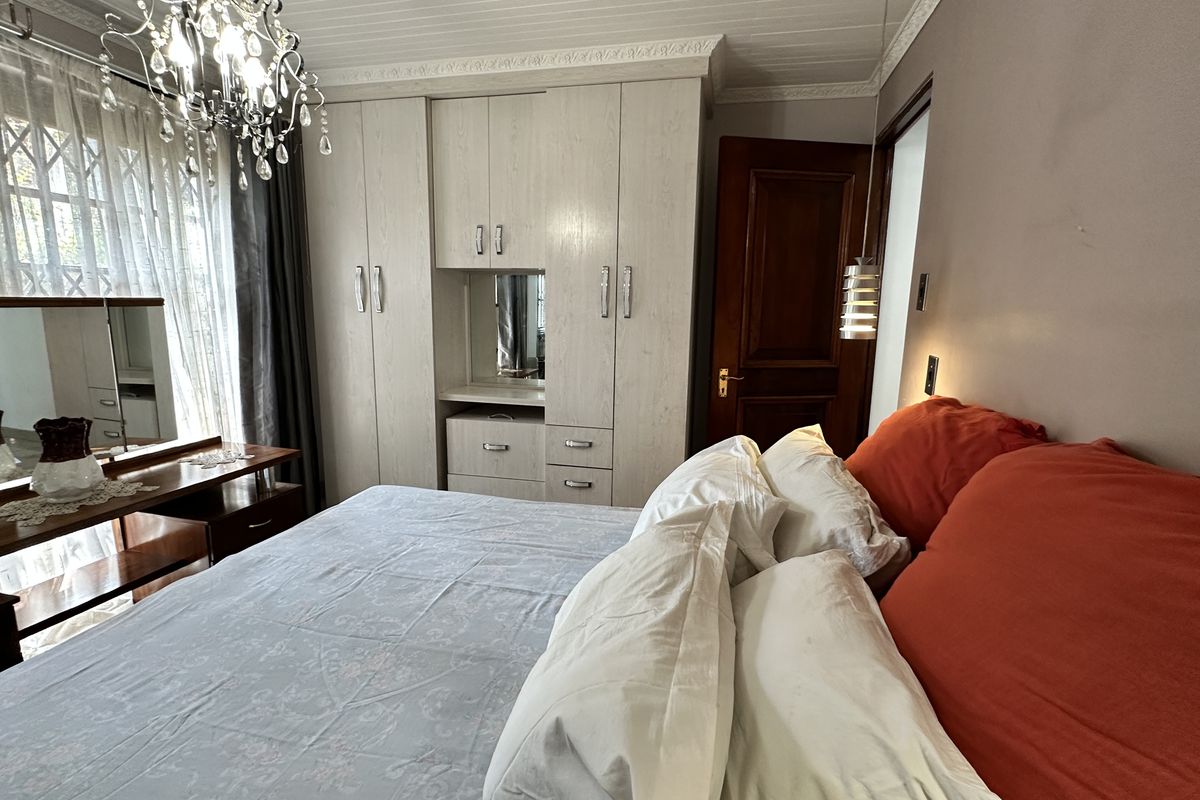 A bedroom featuring built-in light wood cabinetry, crown molding, and a decorative chandelier, providing functional storage and classic architectural detailing.