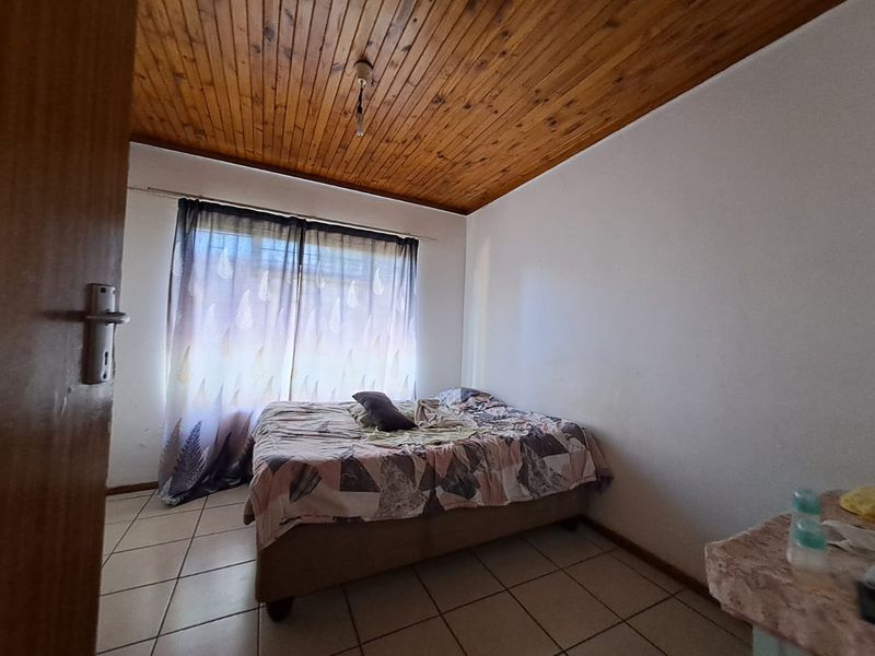A bedroom featuring ceramic floor tiles and a timber tongue and groove ceiling, requiring cosmetic updates to improve its overall condition.