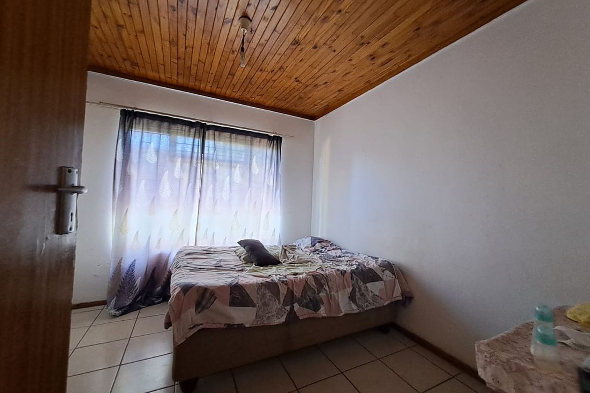 A bedroom featuring ceramic floor tiles and a timber tongue and groove ceiling, requiring cosmetic updates to improve its overall condition.