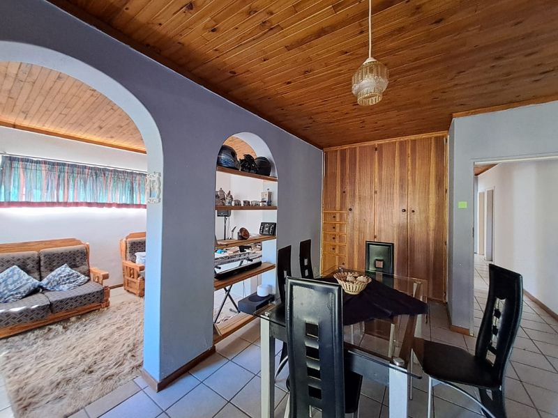 Open plan living and dining area featuring a timber tongue and groove ceiling, built-in wooden cabinetry, and arched architectural details.