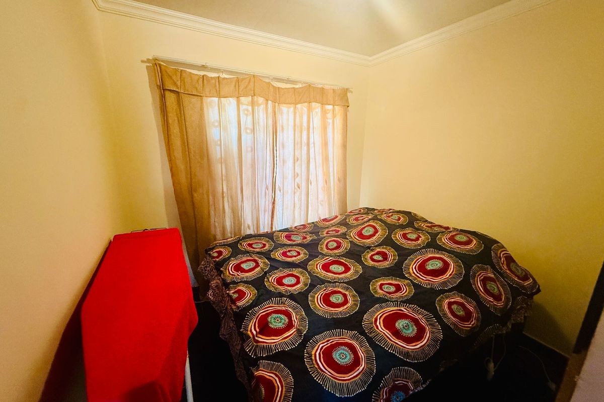 A standard bedroom featuring crown molding and a window with fitted curtain rails.