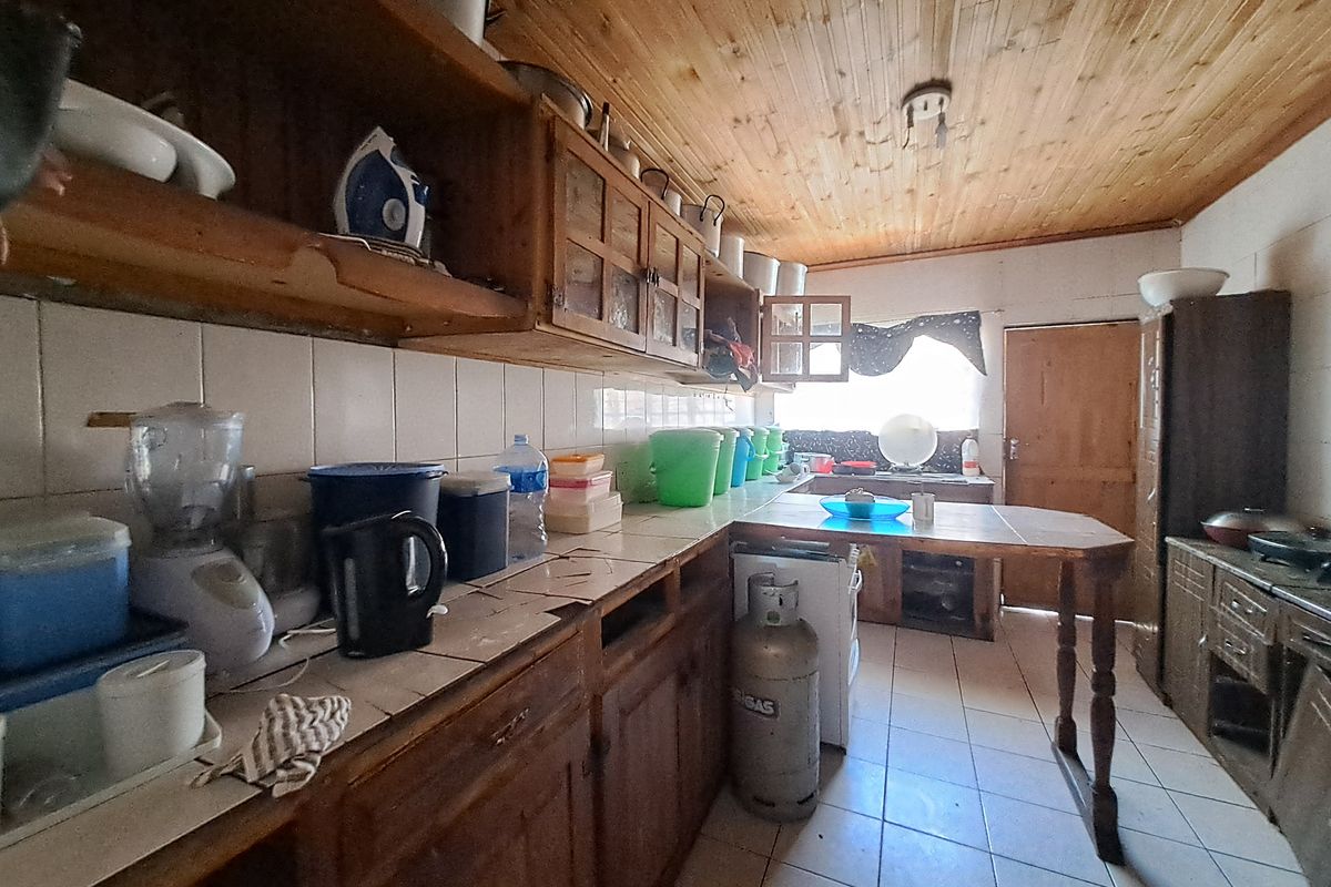 A dated kitchen featuring timber cabinetry, tiled countertops, and a timber-clad ceiling, offering significant potential for a modern renovation.