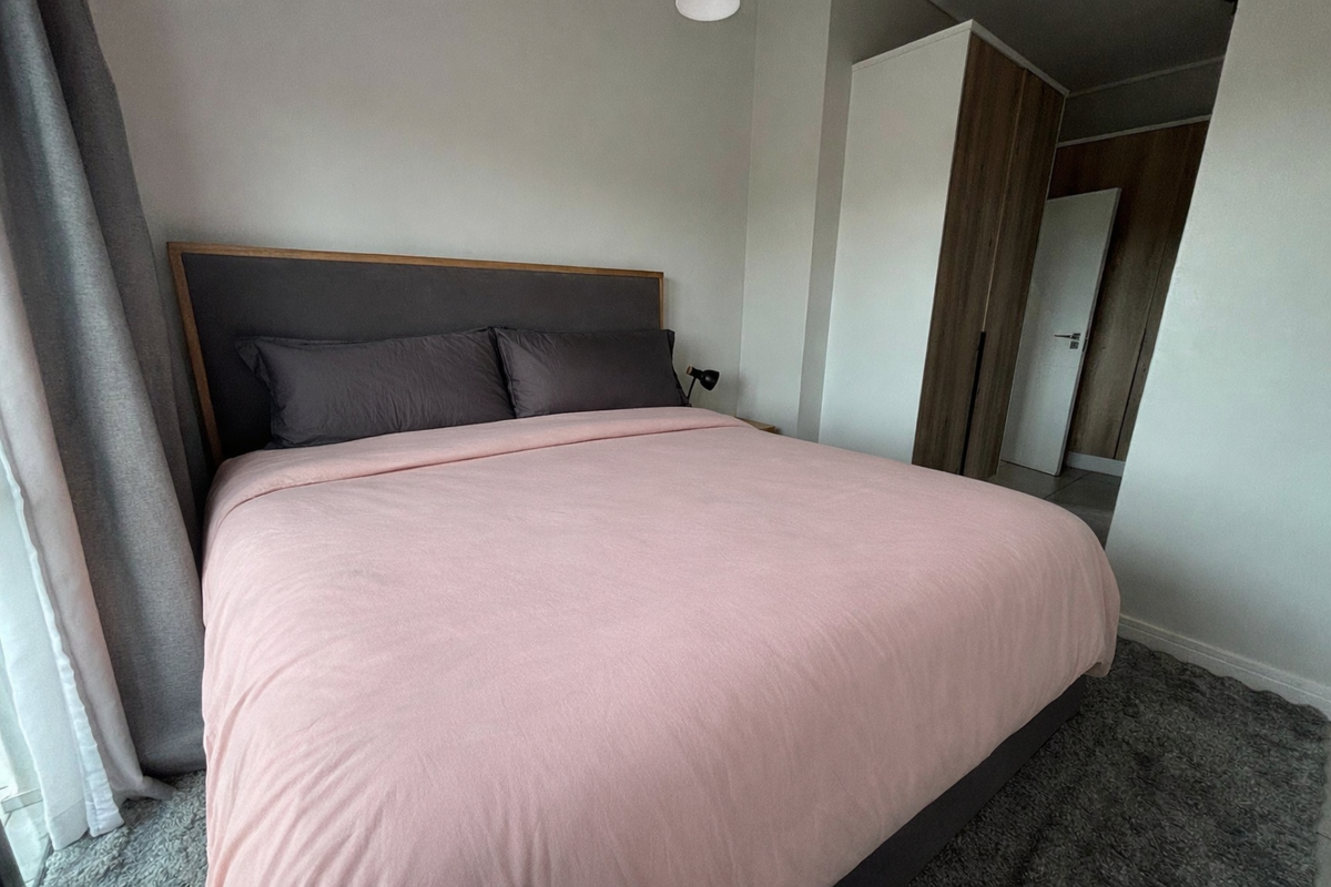A well-maintained bedroom featuring neutral walls, modern built-in wardrobes, and a clean, functional layout.