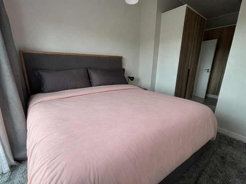 A well-maintained bedroom featuring neutral walls, modern built-in wardrobes, and a clean, functional layout.