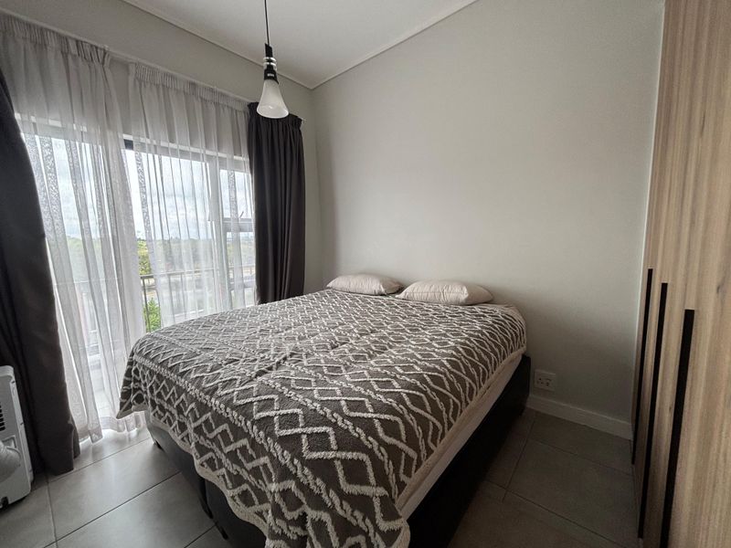 A well-maintained bedroom featuring tiled flooring, a built-in wardrobe, and a sliding glass door providing access to an outdoor area.