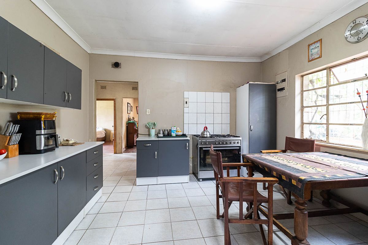 A functional kitchen featuring grey cabinetry, tiled flooring, and a freestanding stove, offering a practical layout with potential for modern updates.