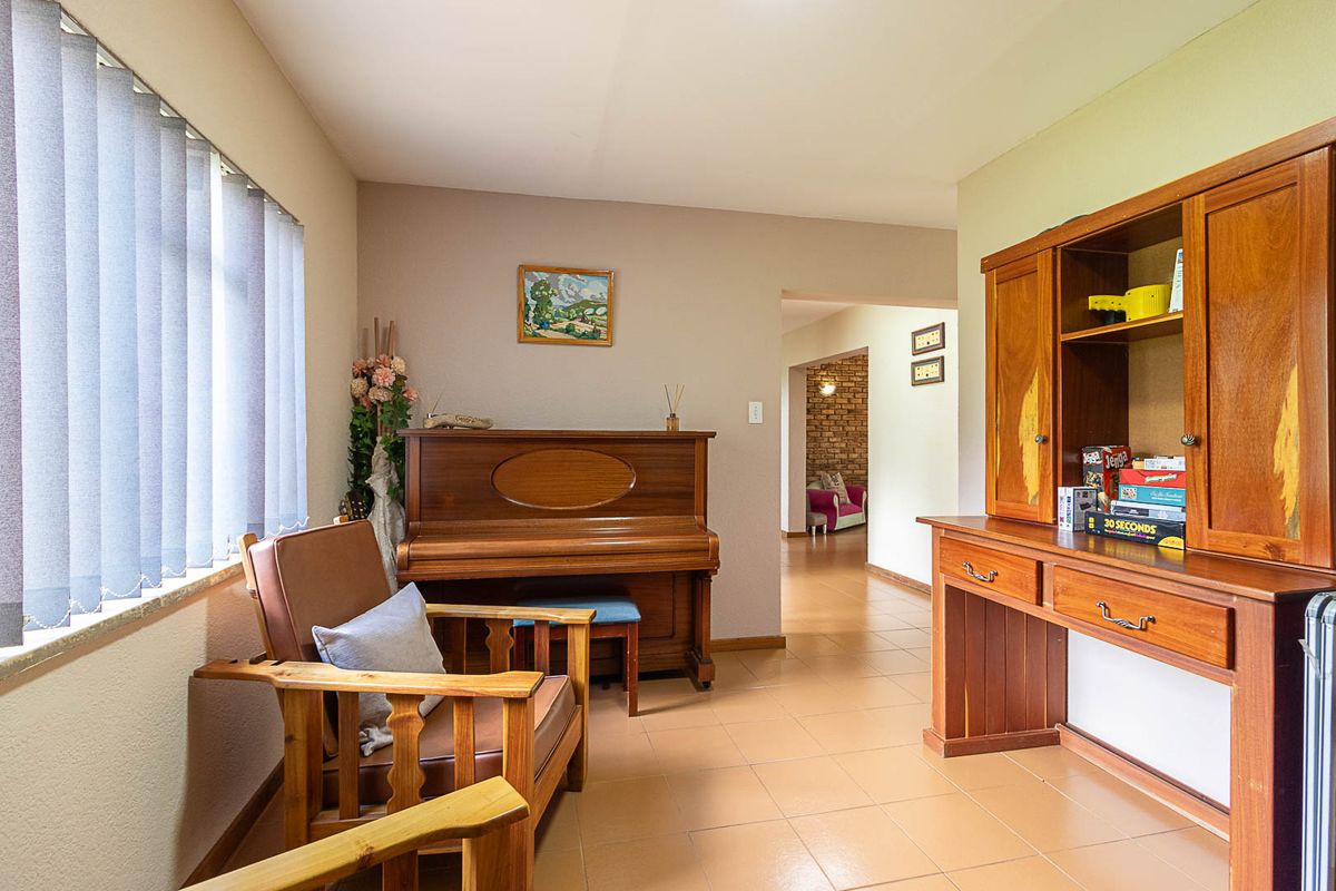 A living area featuring tiled flooring and vertical blinds, providing a neutral space with access to an adjoining room.