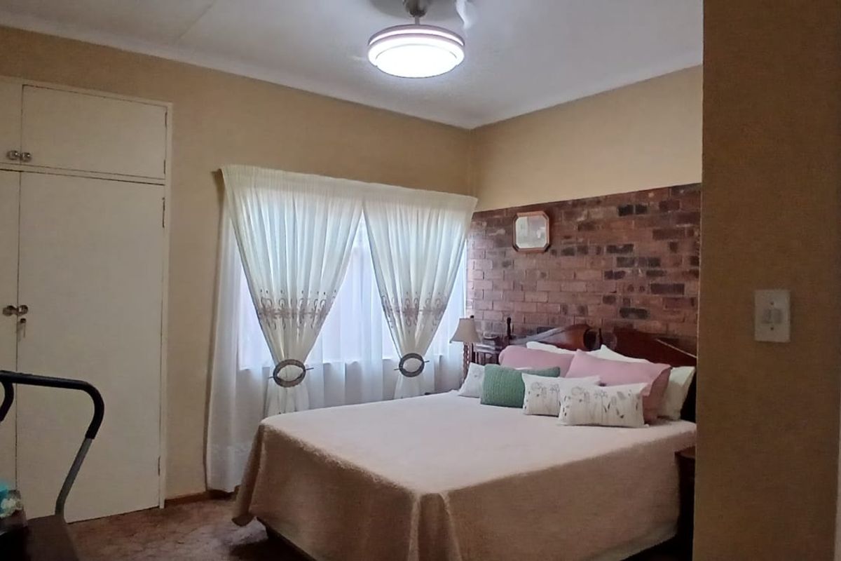 A bedroom featuring a brick accent wall, built-in cupboards, and a ceiling light fixture.