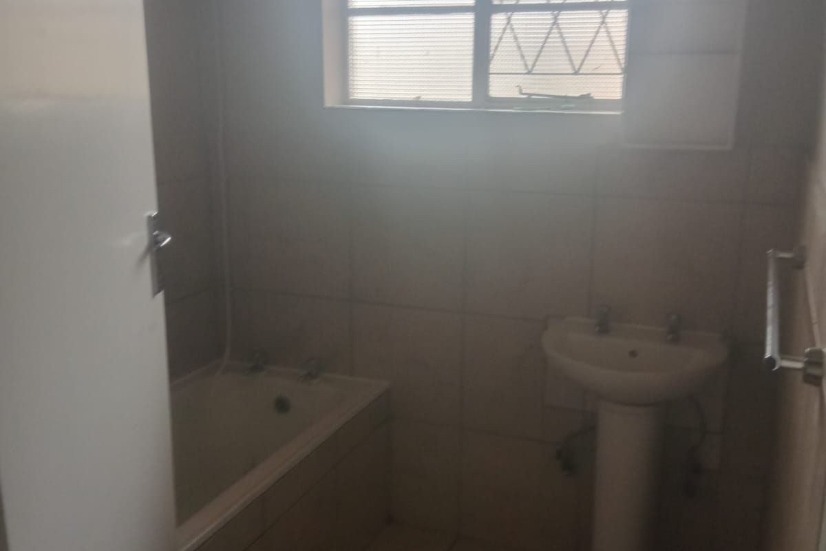 A dated bathroom featuring a standard bathtub, pedestal basin, and tiled flooring, requiring modernization to improve its overall appeal and functionality.