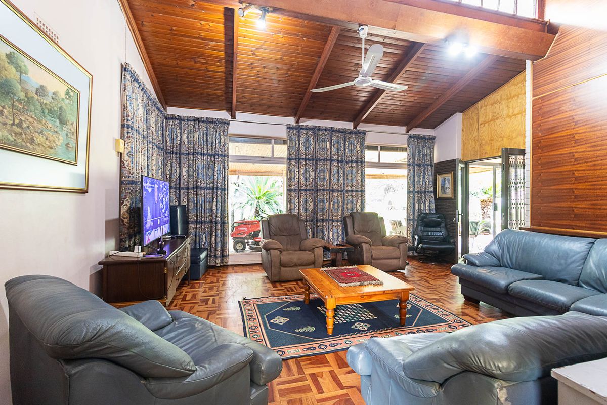 Spacious living room featuring exposed timber ceiling beams, parquet flooring, and large sliding glass doors providing access to the outdoor area.