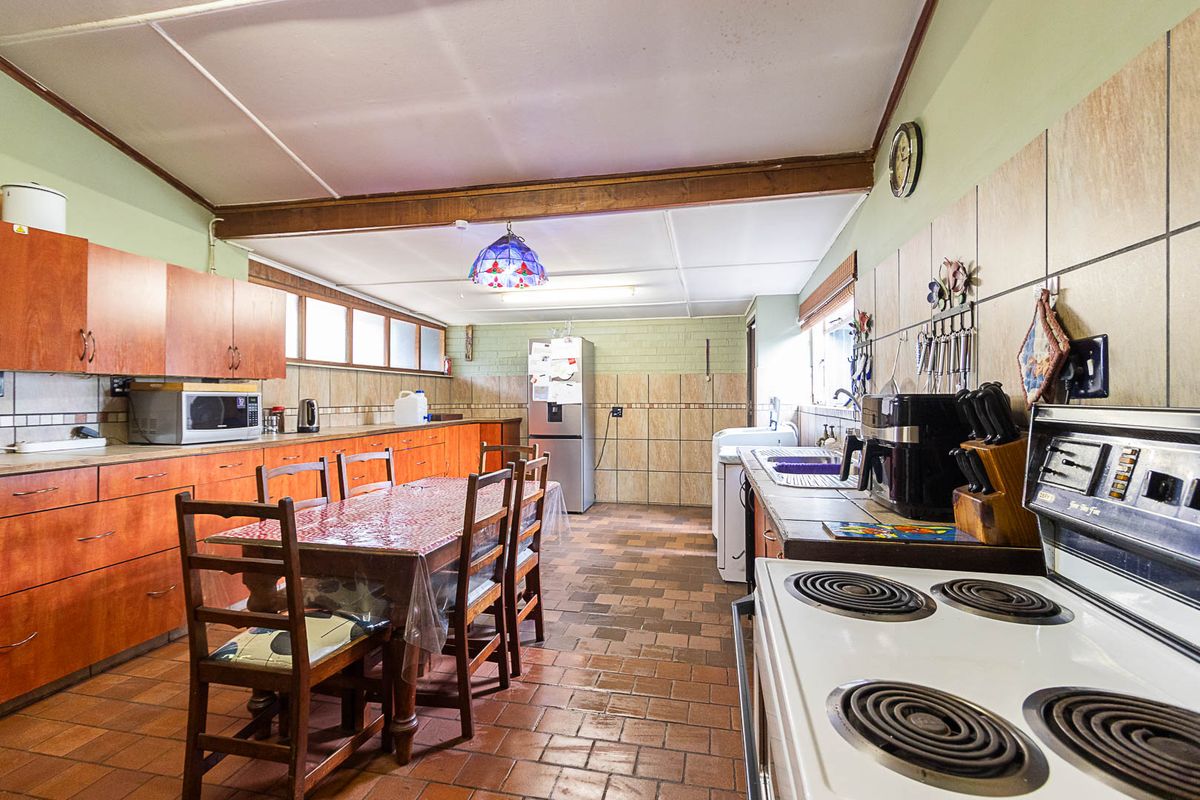 Spacious kitchen featuring extensive timber cabinetry, tiled flooring, and a functional layout with a dedicated dining area and integrated stove.