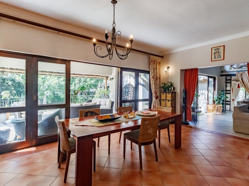 Spacious dining area featuring terracotta floor tiles, a classic wrought iron chandelier, and large timber-framed sliding doors opening to an outdoor patio.