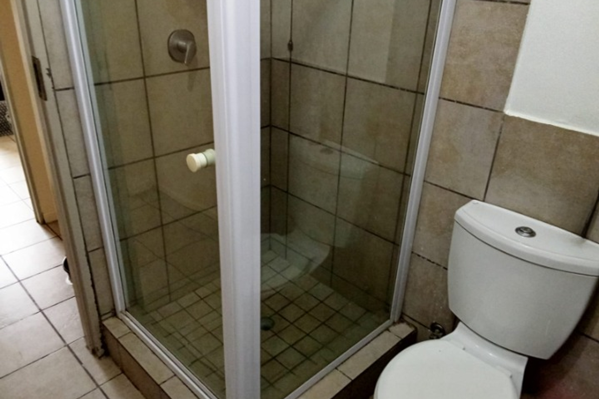 A compact bathroom featuring a corner shower enclosure with glass doors and a standard white ceramic toilet.