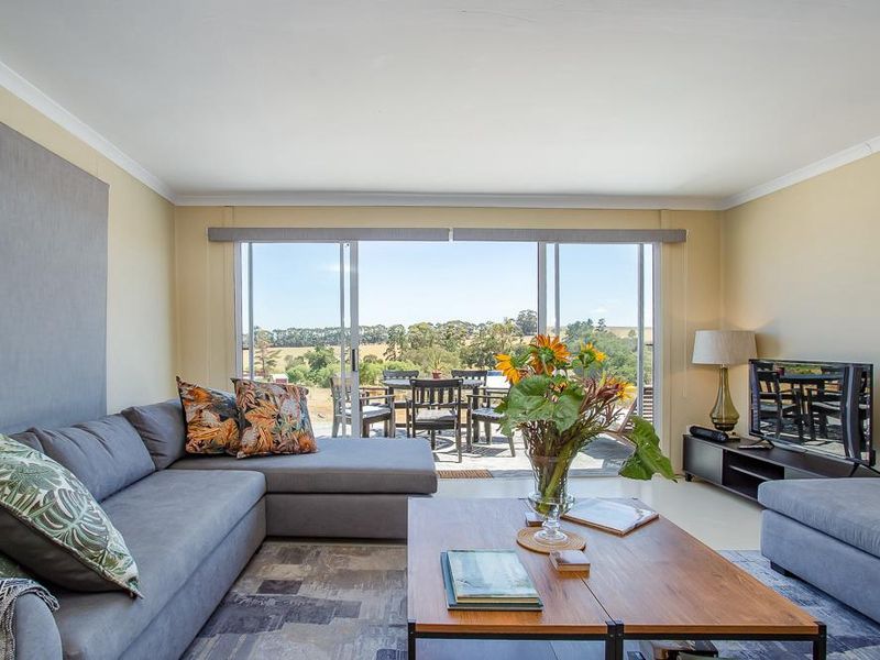 A bright living room featuring large sliding glass doors that provide natural light and access to an outdoor patio area with scenic views.