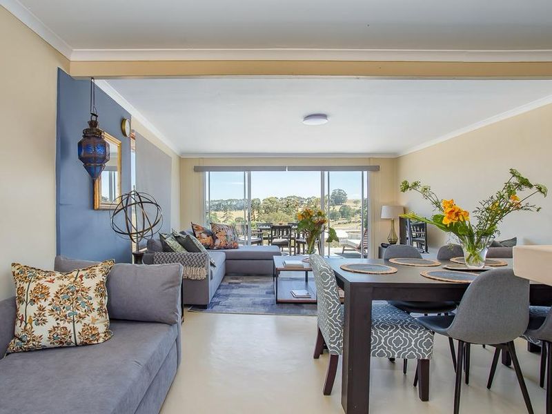 Spacious open-plan living and dining area featuring polished concrete floors and large sliding glass doors that open to a scenic outdoor view.