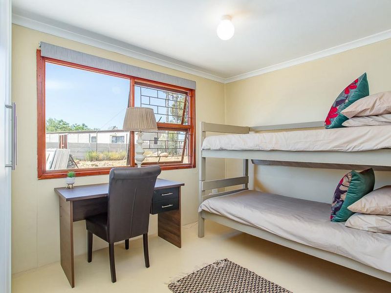 A functional bedroom featuring a timber-framed window with security bars, coved ceiling, and a built-in cupboard.