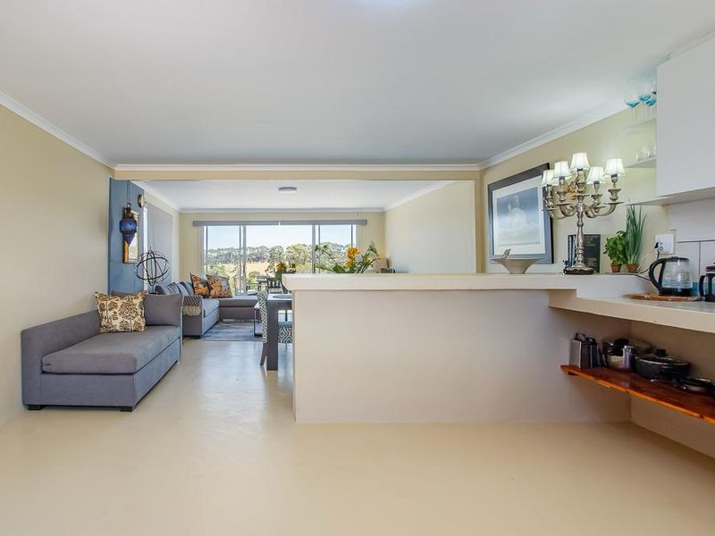 Open plan living and kitchen area featuring a breakfast bar, neutral finishes, and large windows providing natural light and scenic views.