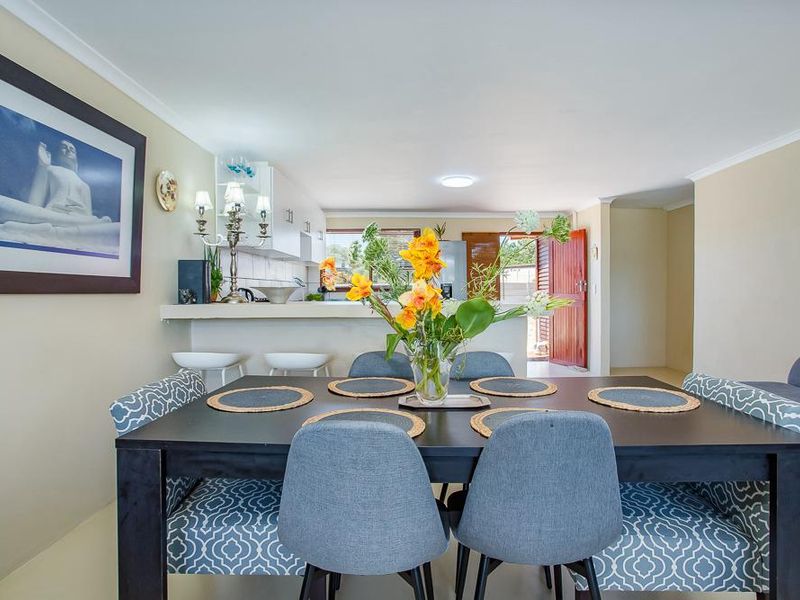 Open-plan living and dining area featuring a breakfast bar, kitchen cabinetry, and neutral finishes, creating a functional and connected space.