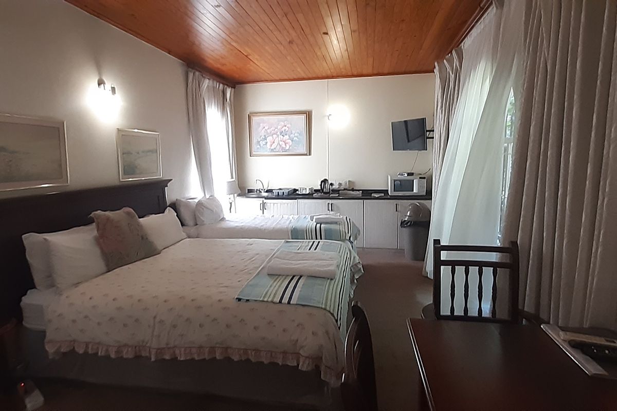 A bedroom featuring a timber ceiling and a compact built-in kitchenette area with sink, offering functional living space.