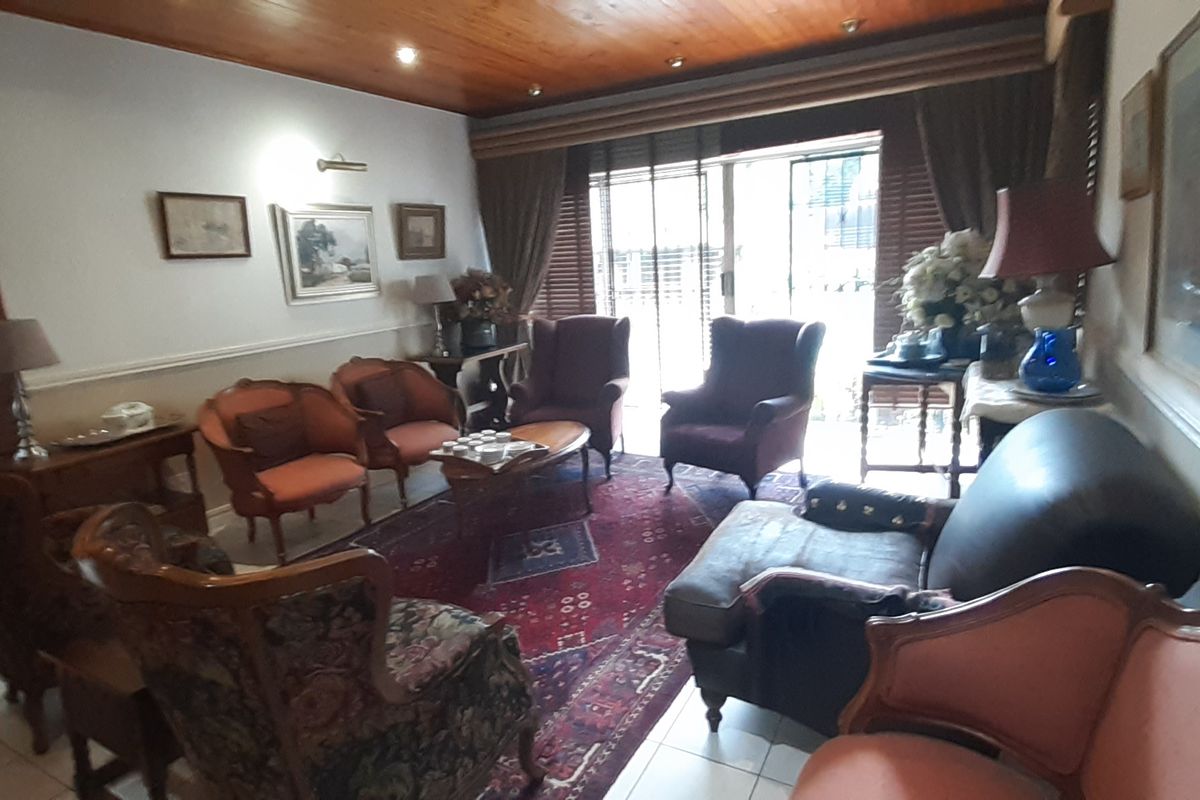 A traditional living room featuring a warm timber ceiling, tiled flooring, and a sliding glass door providing access to the exterior.